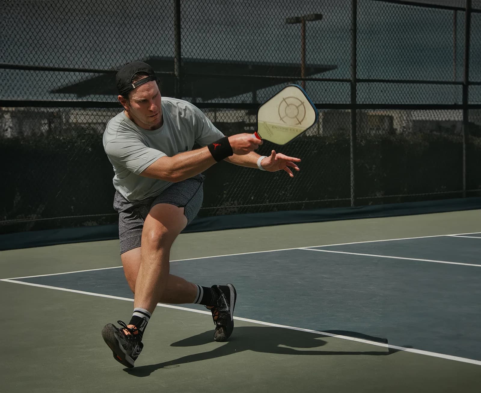 A pickleball player reaching for a forehand on an outdoor court