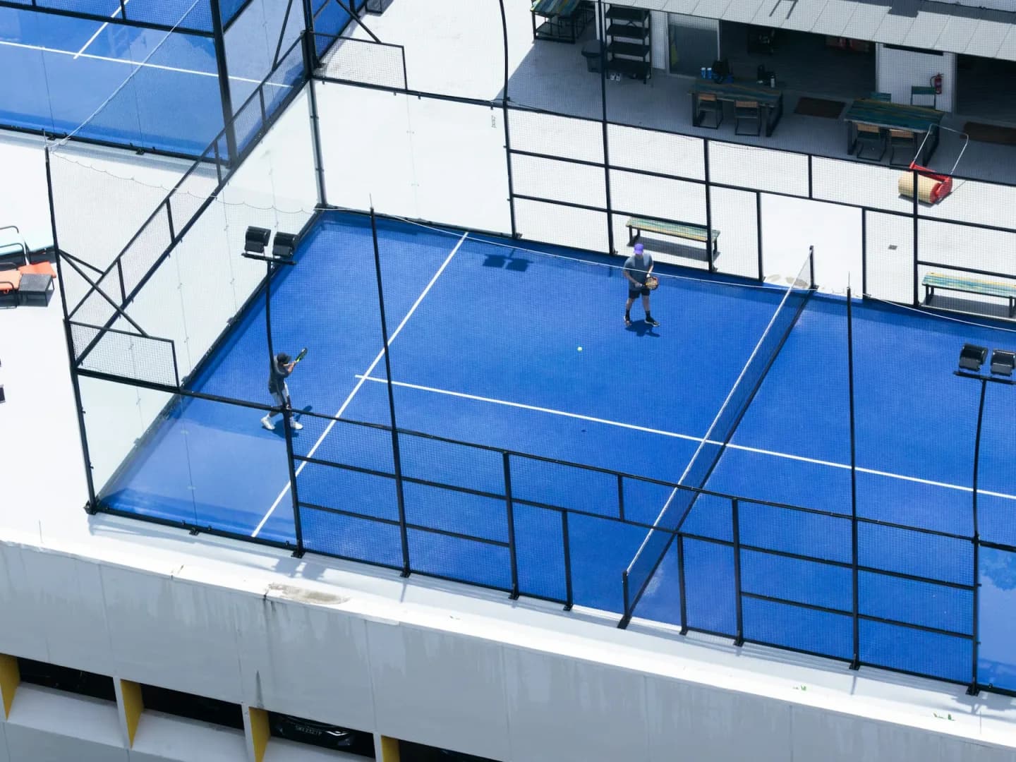 Players on bright blue rooftop courts in a modern city venue