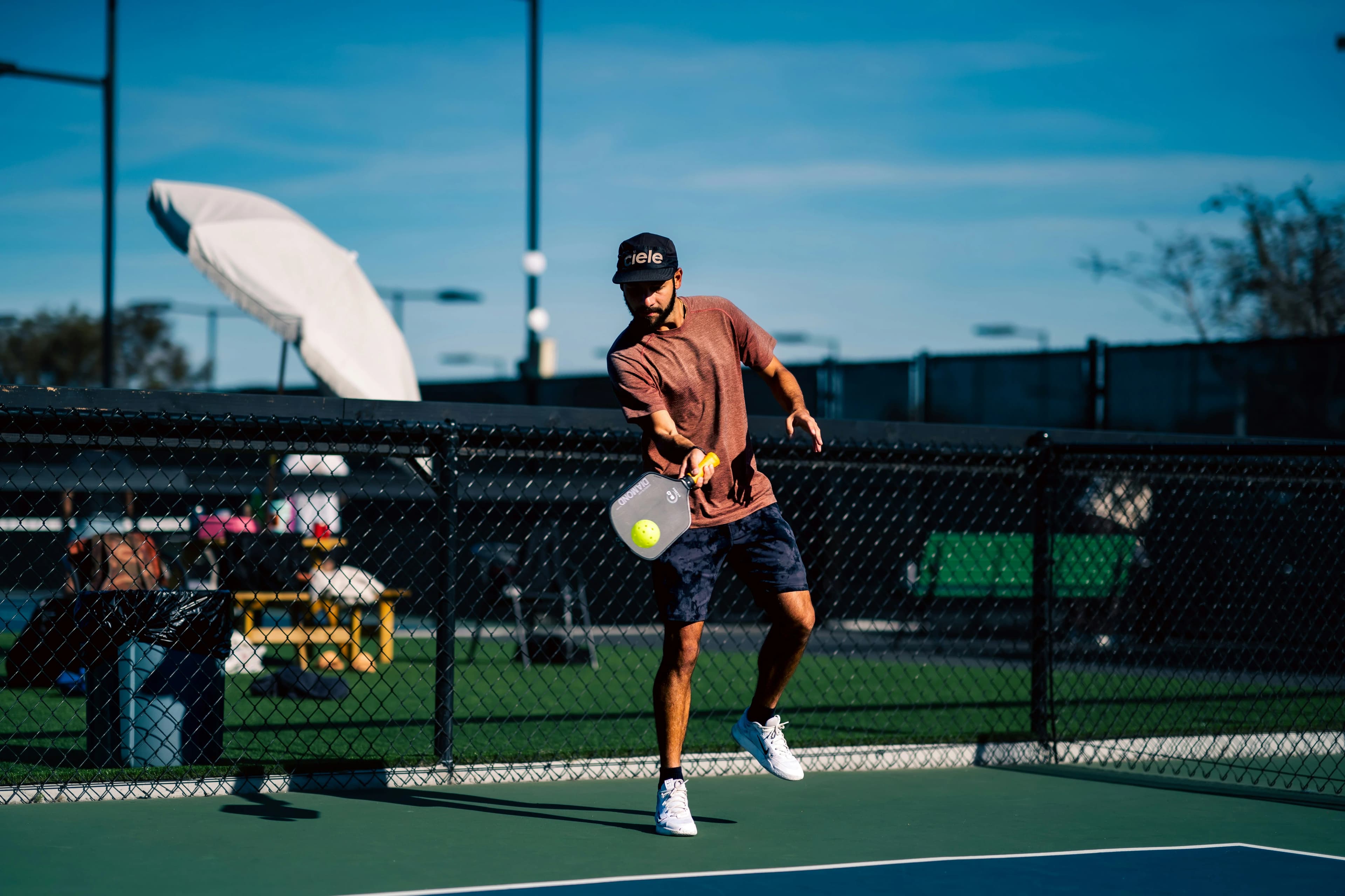 A pickleball player returning a ball on an outdoor court
